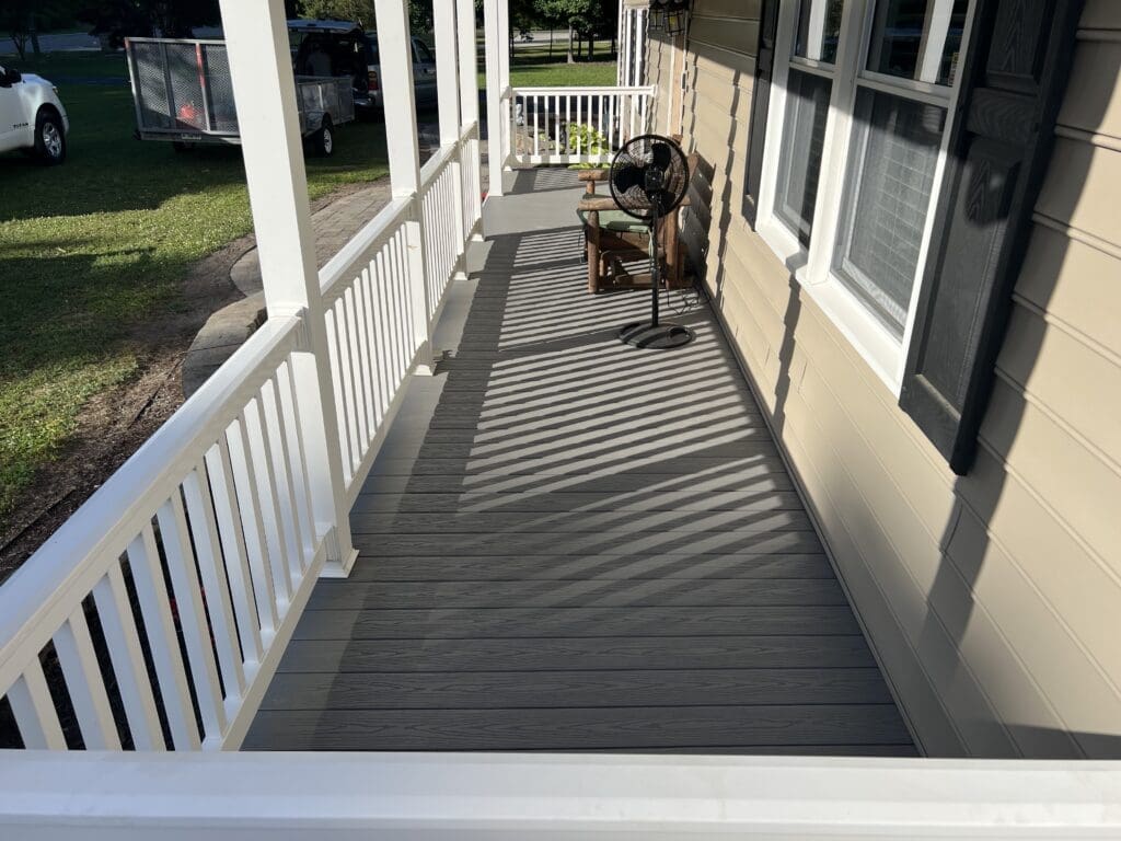 A dog sitting on the porch of a house.