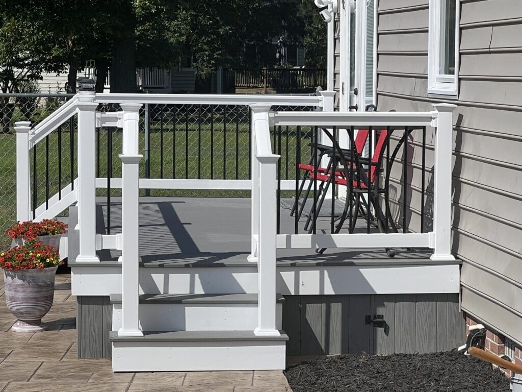 A porch with steps and railings that have been painted white.
