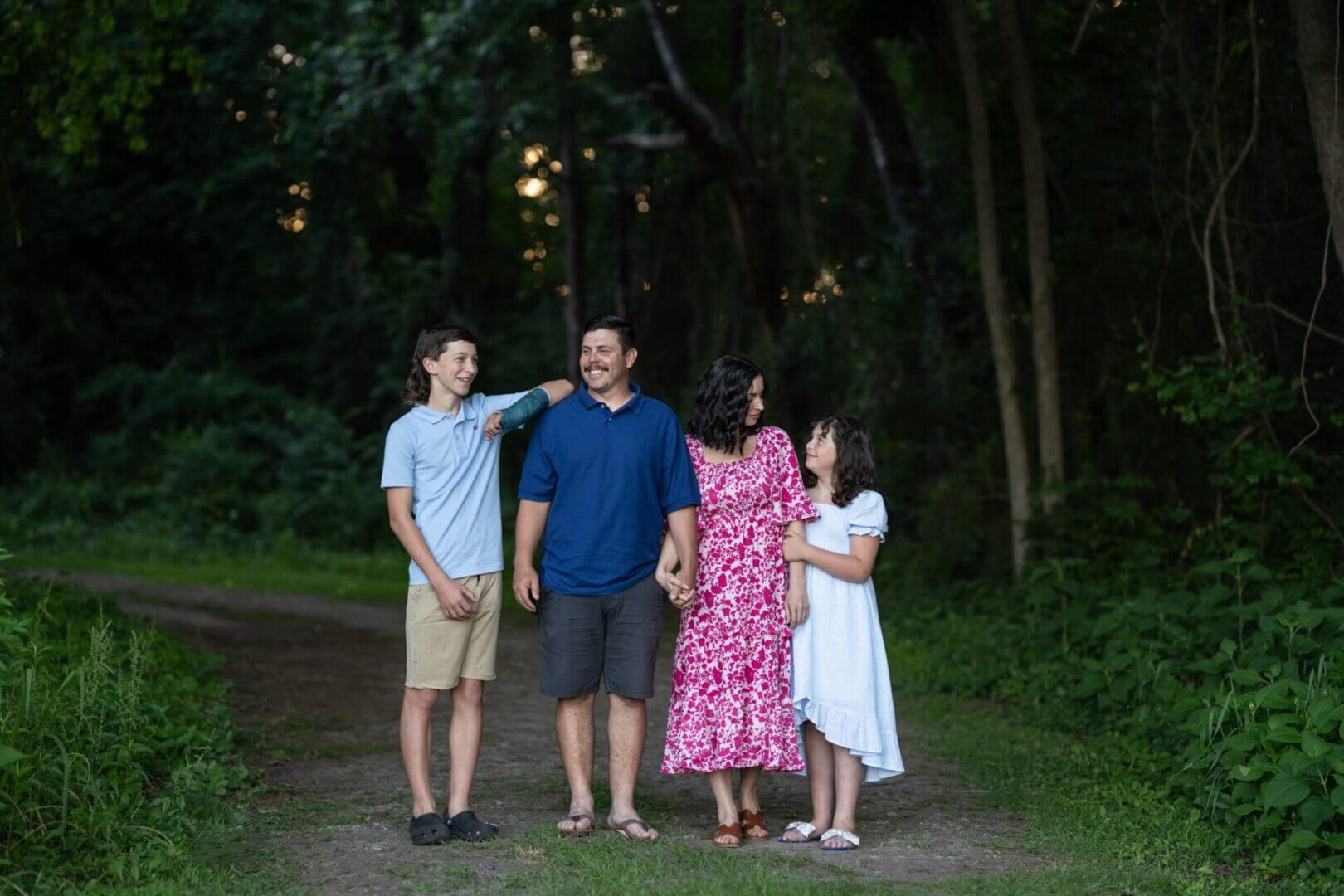 Family walking together in a forest path.